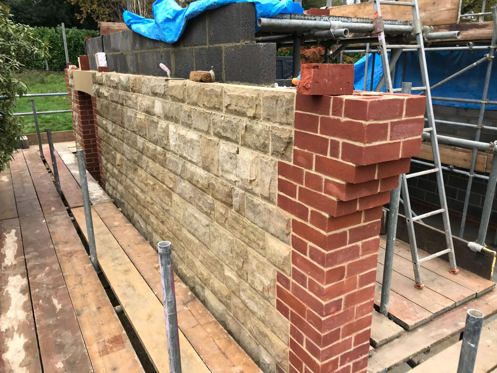 A brick wall under construction on a wooden platform, part of a project by Fost & Co.